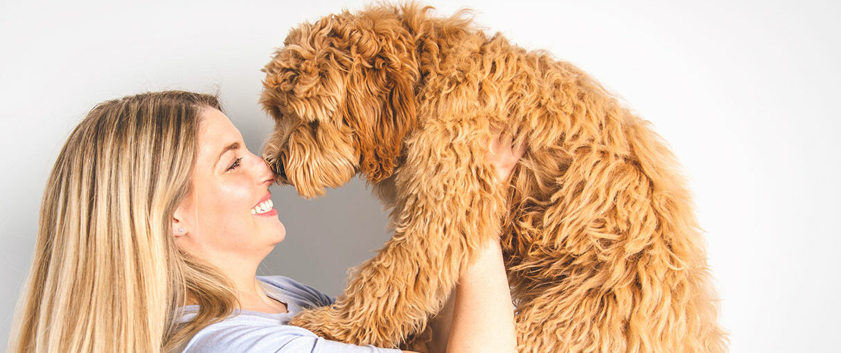 Overjoyed woman holding her goldendoodle